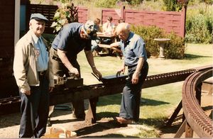 Carl Purinton (right) watches Charlie Smith (center) pump water into the boiler of Carl's little Mogul. Gilbert Greenberg on the left watches Bob Hornsby take pictures. Take at Charlie Puriton's track (Carl's son) in 1985.