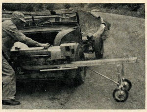 Unloading a heavy locomotive from car rack to portable dolly. The dolly is made of tubing with a strong board on the top. Wheels are rubber tired and the whole device folds up like an ironing board when not in use. Photos by Harry Dixon.