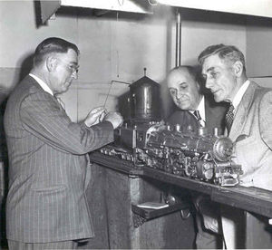 E.D. Moody, General Manager of the Southern Pacific, fills a tender water tank as Victor Shattock and a friend look on.