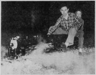 Little Janie Arnold, seven-year-old daughter of Mr. and Mrs. Daniel H. Arnold, Jr., Mt Savage Road, holds on tight as she gets a ride on the live steam locomotive being operated by her cousin, Richard Arnold, 19, also of Mt. Savage Road, who constructed the locomotive with his father, Louis Arnold, and younger brother, William, 16. The steam locomotive which was a tender and flat car capable of hauling three adults runs along a miniature railroad system located in the yard of the home of Louis Arnold, who is a machinist supervisor at the Kelly-Springfield Tire Company plant here. The three members of the family completed the project in about five years, having worked in the basement "roundhouse". From "Cumberland News", 14 December 1959